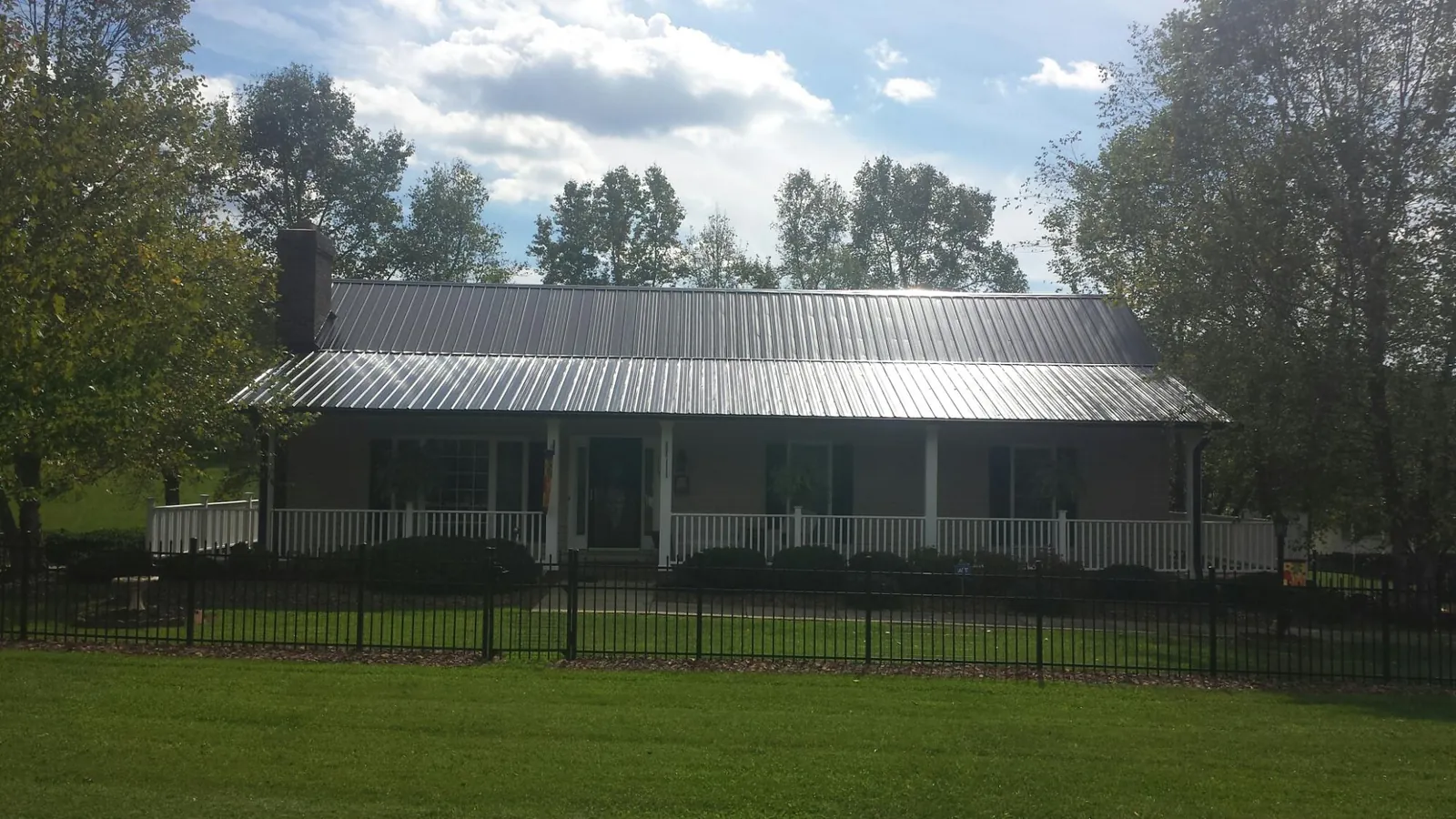 Gray metal roof on a brick ranch with a full width front porch — Gutter Guard Installation work by our crew in Clarksville