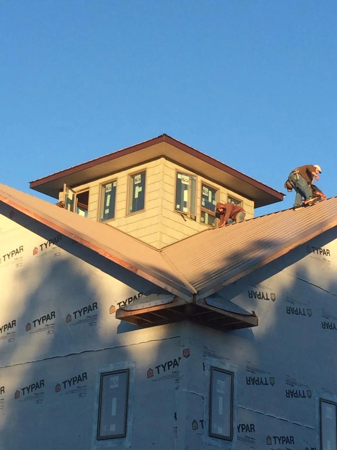 Roofers working around a rooftop cupola on a new metal roof at sunset — Roof Waterproofing in Clarksville by Roofing Brothers